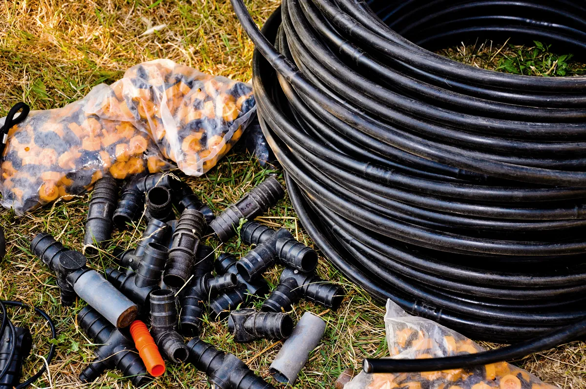 Prepared for planting in early Spring. faucet with red handle for drip irrigation. Drip Irrigation System Close Up. hose for drip irrigation in a skein. DIY drip irrigation system assembly