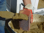 Cement mortar being applied to the butt of the brick