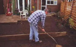 The straight edge acts as a guide to levelling the soil